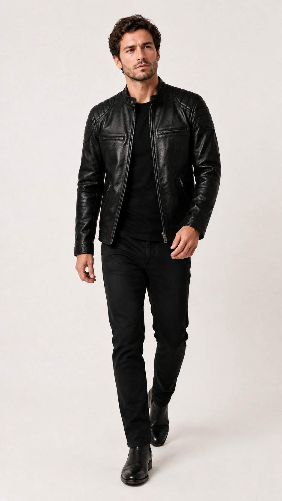 Full-length shot of a man wearing the black biker jacket with black trousers — British model